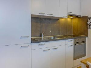 una cocina con armarios blancos y fregadero en Apartment Imperial-1 by Interhome, en Zermatt