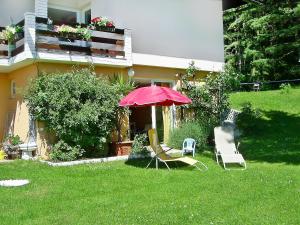 two chairs and an umbrella in the yard of a house at Apartment Keutschach by Interhome in Keutschach am See