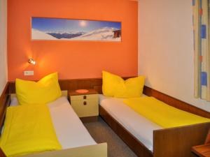 カップルにあるApartment Miramonte - KPL281 by Interhomeのオレンジ色の壁と黄色の枕が備わる客室のベッド2台