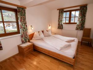 1 dormitorio con 1 cama con sábanas blancas y ventanas en Apartment Plank by Interhome, en Stumm