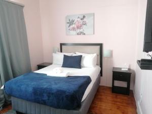 a bedroom with a large bed with a blue blanket at Happy Homes Guest House, Richmond Hill in Port Elizabeth