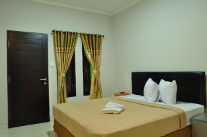 1 dormitorio con 1 cama grande con cortinas de oro en Amerta Home Stay Bali, en Denpasar