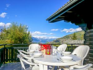 een tafel met witte stoelen op een balkon met uitzicht bij Chalet Sven Heul by Interhome in Nendaz