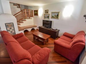 a living room with two red couches and a tv at Chalet Cesa Galadriel-1 by Interhome in Penia