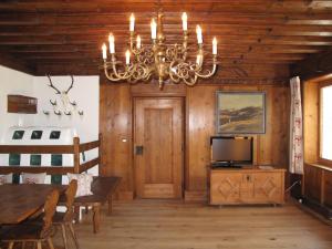 einen Kronleuchter in einem Zimmer mit einem Tisch und einem TV in der Unterkunft Chalet Jagdhaus Biedenegg - FIE215 by Interhome in Fliess