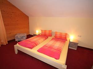 1 Schlafzimmer mit 2 Betten mit orangefarbenen und roten Kissen in der Unterkunft Apartment Sonnenheim-2 by Interhome in Mayrhofen
