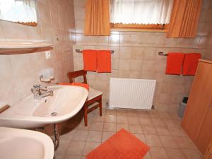 łazienka z umywalką i pomarańczowymi ręcznikami w obiekcie Apartment Sonnenheim-2 by Interhome w Mayrhofen