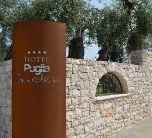un cartello di fronte a un muro di pietra di Hotel Puglia Garden a Vieste