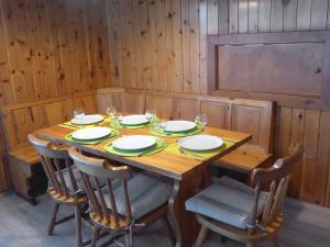 - une table en bois avec des chaises, des assiettes et des verres à vin dans l'établissement Apartment Christiania I F6 by Interhome, à Nendaz