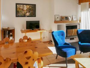 un soggiorno con tavolo in legno e sedie blu di Apartment Muverans I B1 by Interhome a Nendaz