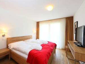 a bedroom with a bed with white sheets and a television at Apartment Zur Matte B-3 by Interhome in Zermatt