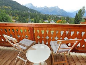 a deck with two chairs and a table and chairs at Chalet Saint Piran by Interhome in Villars-sur-Ollon