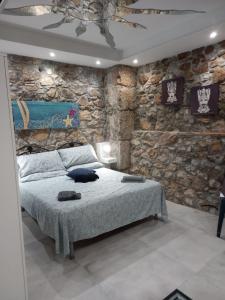 a bedroom with a stone wall with a bed at Cortile delle mura in Cefalù