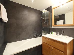 Apartment Zur Matte B-7 by Interhome في زيرمات: حمام مع حوض وحوض استحمام ومرآة