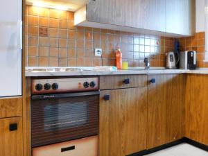 eine Küche mit Holzschränken und einem Herd mit Backofen in der Unterkunft Apartment Luchre by Interhome in Zermatt