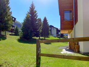 una valla de madera frente a una casa con árboles en Apartment Luchre by Interhome, en Zermatt