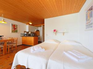 2 weiße Betten in einem Zimmer mit einem Tisch in der Unterkunft Apartment Les Beluardes Bl- 151-2 by Interhome in Taveyannaz