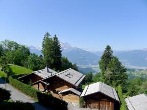 a group of wooden buildings with mountains in the background at Apartment Les Girolles B14 by Interhome in Villars-sur-Ollon