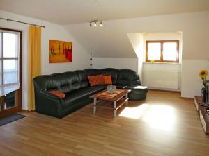 een woonkamer met een zwarte leren bank en een tafel bij Apartment Freisinger-2 by Interhome in Zachenberg