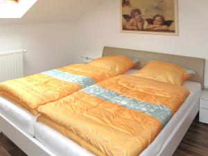 a bed with an orange and blue blanket on it at Apartment Freisinger-2 by Interhome in Zachenberg