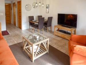 een woonkamer met een tafel en een televisie bij Apartment Les Seracs 1 by Interhome in Villars-sur-Ollon