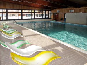 a large swimming pool with lounge chairs in a building at Studio Résidence Dixence-10 by Interhome in Les Collons