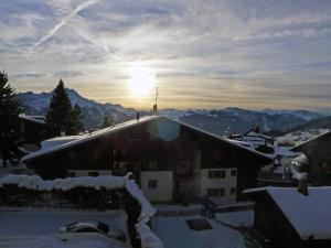 a snow covered roof of a house with the sun in the background at Apartment Villars Soleil A27 by Interhome in Villars-sur-Ollon