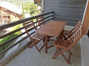 d'une table en bois et de deux chaises sur un balcon. dans l'établissement Apartment Villars Soleil A27 by Interhome, à Villars-sur-Ollon