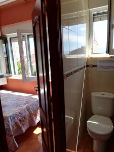 łazienka z toaletą, łóżkiem i oknami w obiekcie O Encontro w mieście Fisterra