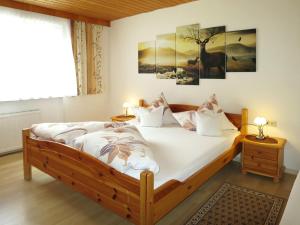 een slaapkamer met een bed met witte lakens en een hert aan de muur bij Apartment Daheim – Wildspitz by Interhome in Plangeross