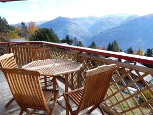 a wooden table and chairs on a balcony with mountains at Apartment Ardève No 11 by Interhome in Ovronnaz