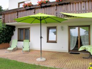 a green umbrella in front of a house at Apartment Alpenblick by Interhome in Brenden