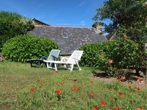Plozévet的住宿－Holiday Home Les Hortensias - PZV107 by Interhome，两把白色的椅子和一张桌子在花田里