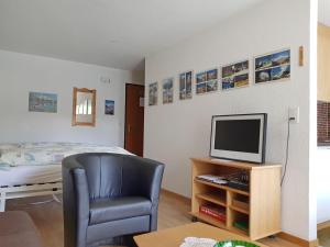 Zimmer mit einem Stuhl, einem TV und einem Bett in der Unterkunft Apartment Castor und Pollux-2 by Interhome in Täsch
