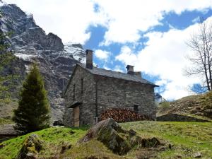 una casa de piedra en una colina con montañas en el fondo en Holiday Home Dara Cotta by Interhome en Alpe di Scieru