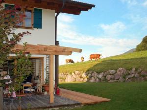 a house with a deck with cows on a hill at Holiday Home Maiergschwendt by Interhome in Ruhpolding