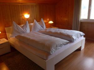 een slaapkamer met een bed met witte lakens en kussens bij Apartment Chalet Bärgsunna-3 by Interhome in Grindelwald