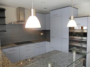una cocina con armarios blancos y dos luces colgantes en Apartment ufem Stutz by Interhome, en Grindelwald
