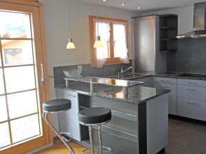 una cocina con encimera y taburetes. en Apartment ufem Stutz by Interhome, en Grindelwald