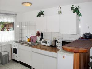 BuchholzにあるHoliday Home Zum Blauen Pfau by Interhomeの白いキャビネットとシンク付きのキッチン