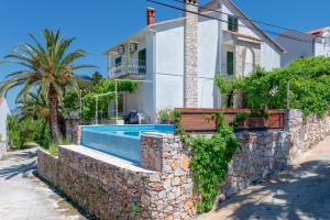 a house with a stone wall and a swimming pool at Villa ToTa Glamur in Jelsa