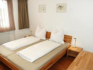 Cette chambre comprend 2 lits avec des draps et des oreillers blancs. dans l'établissement Apartment Valetta Sura by Interhome, à Flims