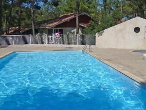 a large blue swimming pool in front of a house at Holiday Home Golf Loisirs-1 by Interhome in Lacanau-Océan