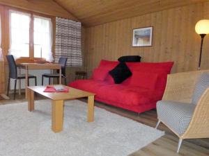 a living room with a red couch and a table at Apartment Chalet Doris-1 by Interhome in Grindelwald