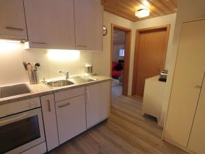 a kitchen with white cabinets and a sink at Apartment Chalet Doris-1 by Interhome in Grindelwald