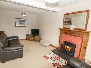 a living room with a couch and a fireplace at Rhug Villa in Nefyn