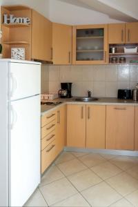 cocina con armarios de madera y nevera blanca en Apartment Toni - SIB242 by Interhome en Grebaštica
