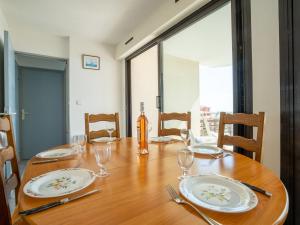 a wooden table with plates and wine glasses on it at Apartment Le Sunset-Cap Sud-7 by Interhome in Cap d'Agde