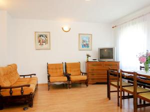un soggiorno con sedie, TV e tavolo di Apartment Dorka - RAB303 by Interhome a Rab