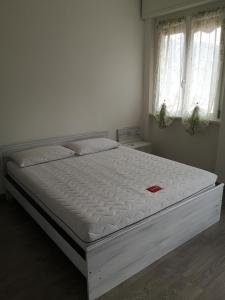 1 cama blanca en un dormitorio con 2 ventanas en Lilla, en Bellagio